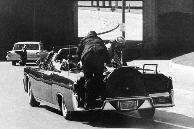 Clint Hill, de dos, se précipite sur la voiture présidentielle, le 22 novembre 1963 à Dallas (Texas), pour tenter de sauver le président américain John F. Kennedy, alors que la première dame, Jacqueline Kennedy, monte sur le coffre.