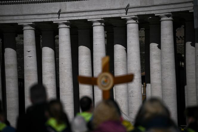 Os peregrinos caminham com um cruzamento no local Saint-Pierre, no Vaticano, segunda-feira, 3 de março de 2025, enviando suas orações ao papa Francisco, ainda hospitalizadas.