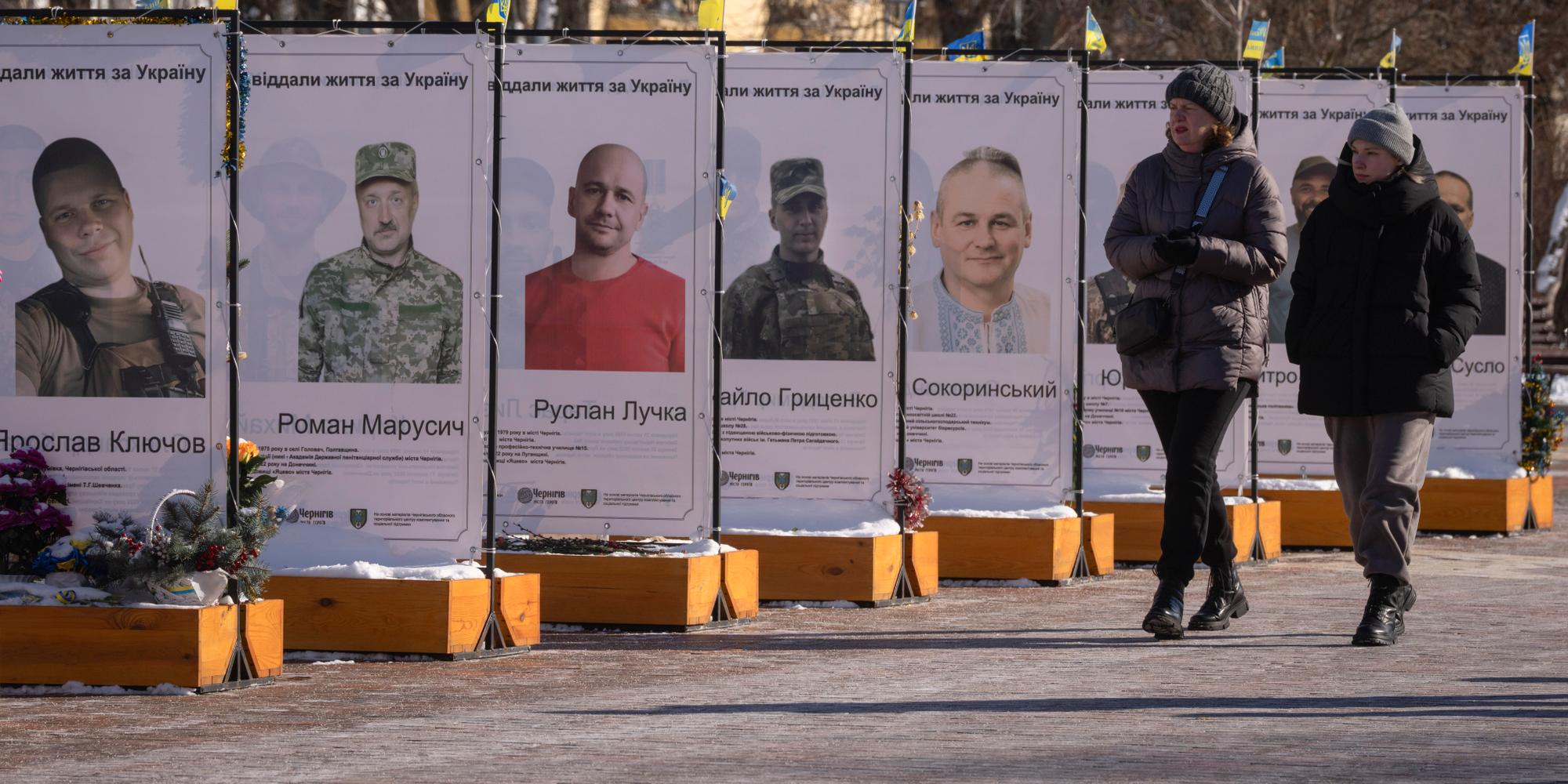 Des passants marchent à côté de photos d’habitants qui ont rejoint l’armée ukrainienne et qui ont été tués dans les combats contre la Russie, lors d’un mémorial aux soldats tombés à Tchernihiv, en Ukraine, le 16 février 2025.