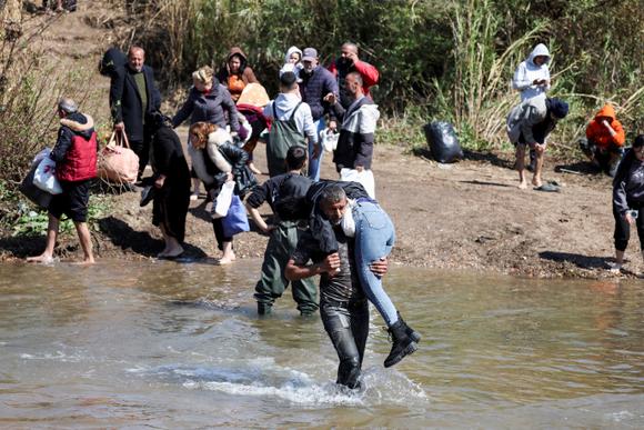 Des Syriens traversent à pied la rivière Al-Kabir, qui sert de frontière entre le Liban et la Syrie, pour se réfugier dans le gouvernorat libanais de l’Akkar, limitrophe de la Syrie, le 11 mars 2025.