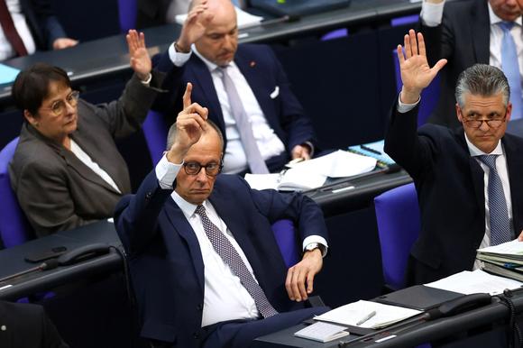 Le futur chancelier allemand, Friedrich Merz, lève la main lors d’une session extraordinaire au Bundestag pour un vote visant à adopter une réforme des règles constitutionnelles de la dette et mettre en place un fonds d’infrastructure de 500 milliards d’euros, à Berlin, le 18 mars 2025.