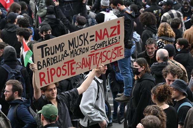 A protestor holds a sign reading "Trump, Musk = Nazi, Bardella & Macron accomplices" during a demonstration on Place de la Republique in Paris on March 22, 2025, as part of the international day against racism and fascism.