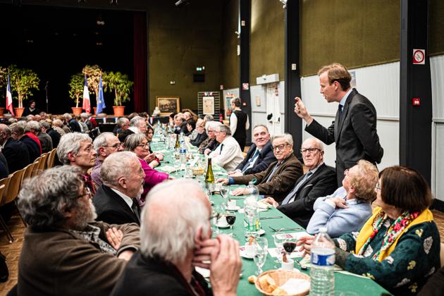 Independent MP Harold Huwart (standing, right) speaks with attendees at the 117th Marceau banquet, held in a village hall in the central French town of Mainvilliers, on March 14, 2025.