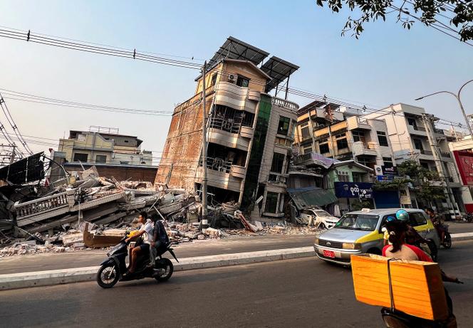 Commuters drive past a building that collapsed, in the aftermath of a strong earthquake, in Mandalay, Myanmar, March 30, 2025. 