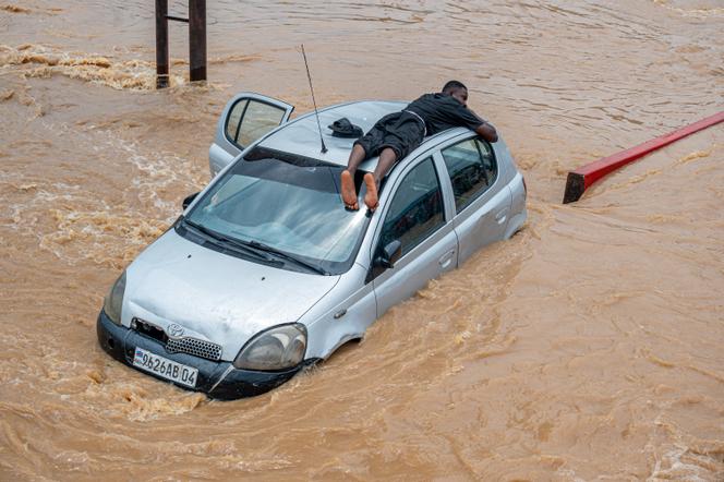 Un homme se réfugie sur le toit d’une voiture lors d’inondations à Kinshasa, le 6 avril 2025.