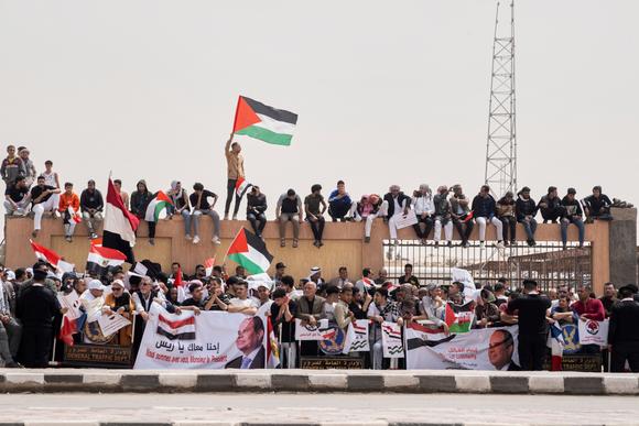 Des Egyptiens brandissent des drapeaux palestiniens et égyptiens pour saluer un convoi transportant le président Abdel Fattah Al-Sissi et son homologue français, Emmanuel Macron, lors de leur visite dans la ville d’El-Arich, dans le nord de la péninsule du Sinaï, à environ 50 kilomètres à l’ouest de la frontière avec la bande de Gaza, en Egypte, le 8 avril 2025.