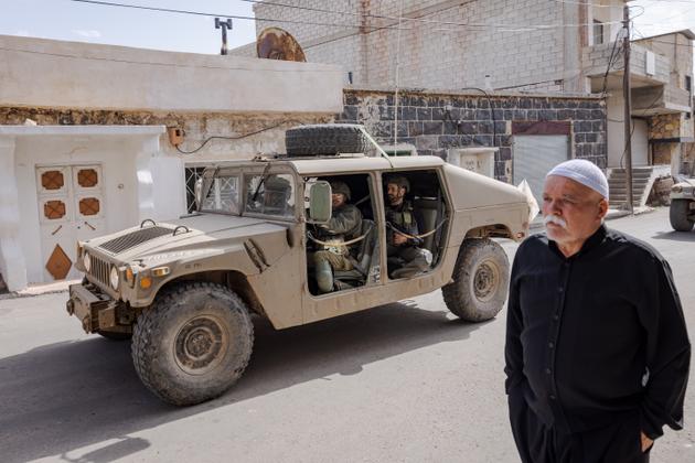 Un convoi de plusieurs blindés de l’armée israélienne passe devant les habitants dans le centre du village druze de Hader (Syrie), le 29 mars 2025.