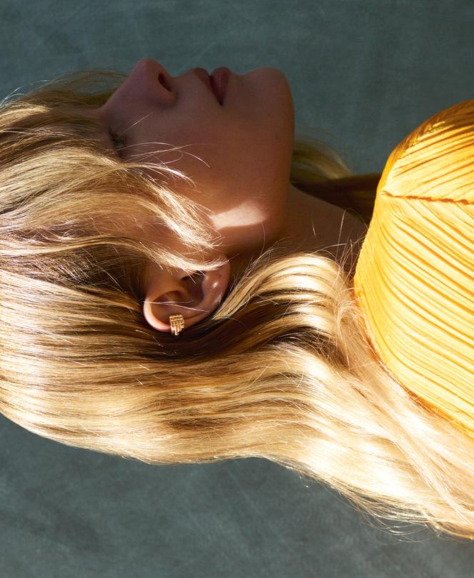 Clip d’oreille Antifer, en or rose, Repossi, 2 250 €. Top Pleats Please, Issey Miyake.