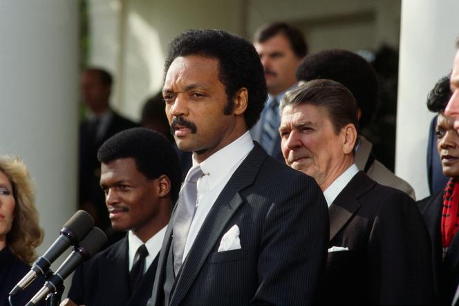 O ativista americano dos direitos civis Jesse Jackson, durante uma cerimônia em homenagem ao piloto do exército dos EUA Robert O. Goodman (à esquerda) capturado na Síria, cuja libertação Jackson havia negociado, Washington, 4 de janeiro de 1984. Atrás dele, o presidente dos EUA Ronald Reagan.