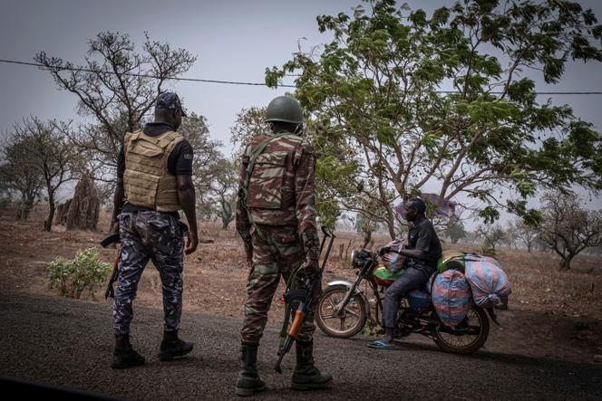 Un policier et un soldat béninois arrêtent un motocycliste à un poste de contrôle à l’extérieur de Porga, au Bénin, le 26 mars 2022.