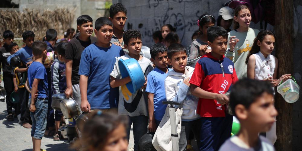 Des jeunes Palestiniens font la queue pour recevoir une portion de nourriture d’une cuisine caritative dans le camp de réfugiés d’Al-Boureij, dans le centre de la bande de Gaza, le 29 avril 2025. - EYAD BABA / AFP
