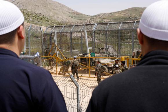 Des soldats israéliens montent la garde tandis que des hommes druzes manifestent en solidarité avec la communauté druze syrienne, près de la barrière frontalière à Majdal Shams, sur le plateau du Golan annexé par Israël, le 30 avril 2025.