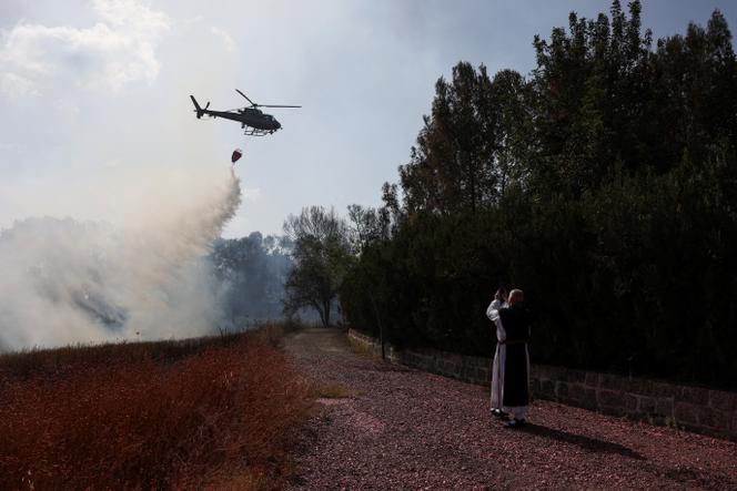 Un moine cistercien photographie un hélicoptère bombardier d’eau, près de Latroun, dans le centre d’Israël, le 1er mai 2025.