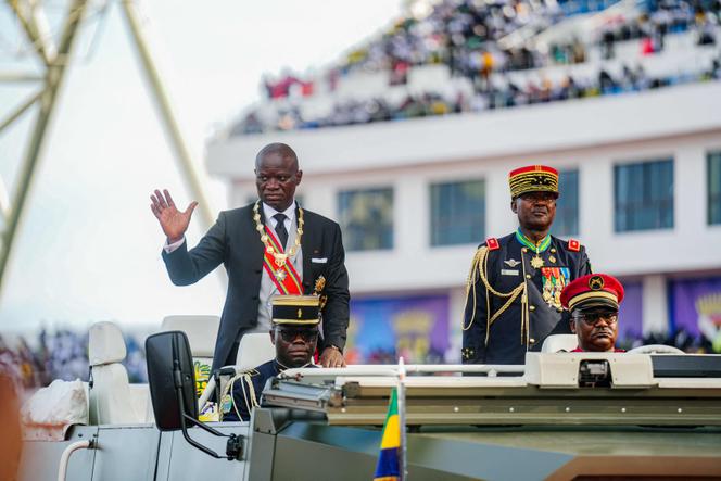 President of Gabon Brice Oligui Nguema (L) waves to the crowd from a vehicle as he parades around the arena during his swearing-in ceremony at a stadium in Libreville on May 3, 2025.