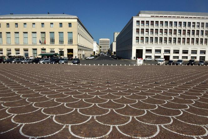 Cette photo prise à Rome, en juillet 2014, depuis le parvis du Palazzo dei Congressi (« Palais des congrès »), montre le Palazzo della civilta del lavoro (« Palais de la civilisation du travail »), au centre, ou « Square Colosseum », icône de l’architecture fasciste, situé dans le quartier de l’Esposizione Universale Roma (EUR), également connu sous le nom de « E.42 ».