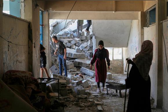 Des Palestiniens dans les décombres d’une école abritant des réfugiés après une frappe israélienne, à Al-Boureij, dans la bande de Gaza, le 7 mai 2025.