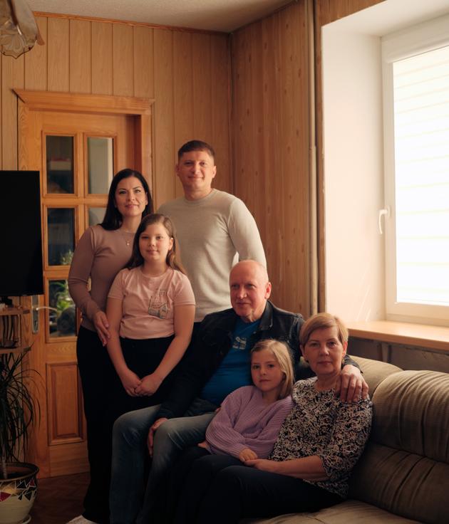 La famille d’Auguste Venslauskaite, 7 ans (au centre, sur le canapé), chez elle à Kybartai (Lituanie), le 24 avril 2025. Debout, sa mère, Toma Venslauskiene, son père, Edvardas Venslauskas, et sa sœur, Rusne. Assis, les parents de Toma, Gentautas Dobiliauskas et Elena Dobiliauskiene.