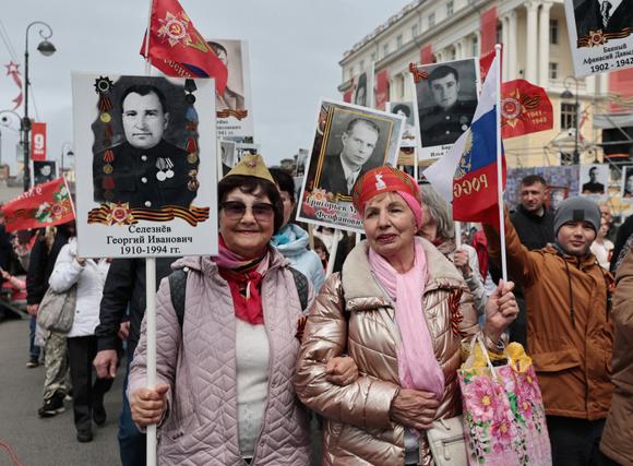 Des Russes portent des portraits de soldats et d’anciens combattants de l’Armée rouge, à Vladivostok, en Russie, le 9 mai 2025.