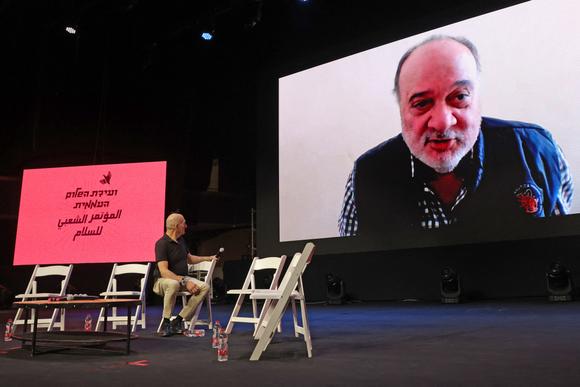 L’ancien ministre des affaires étrangères palestinien, Nasser Al-Kidwa, parle en visioconférence, alors que l’ancien premier ministre israélien, Ehud Olmert, sur scène, l’écoute, au Centre international de conventions de Jérusalem, vendredi 9 mai 2025.