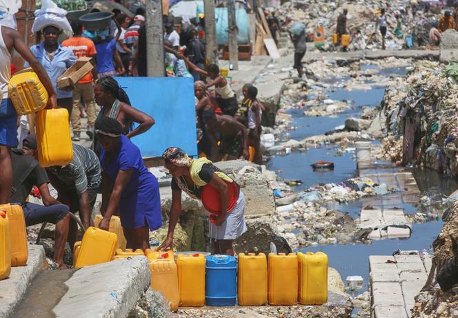 Des gens font la queue pour remplir leurs récipients d’eau potable provenant de tuyaux souterrains cassés à Port-au-Prince (Haïti), le 9 mai 2025.