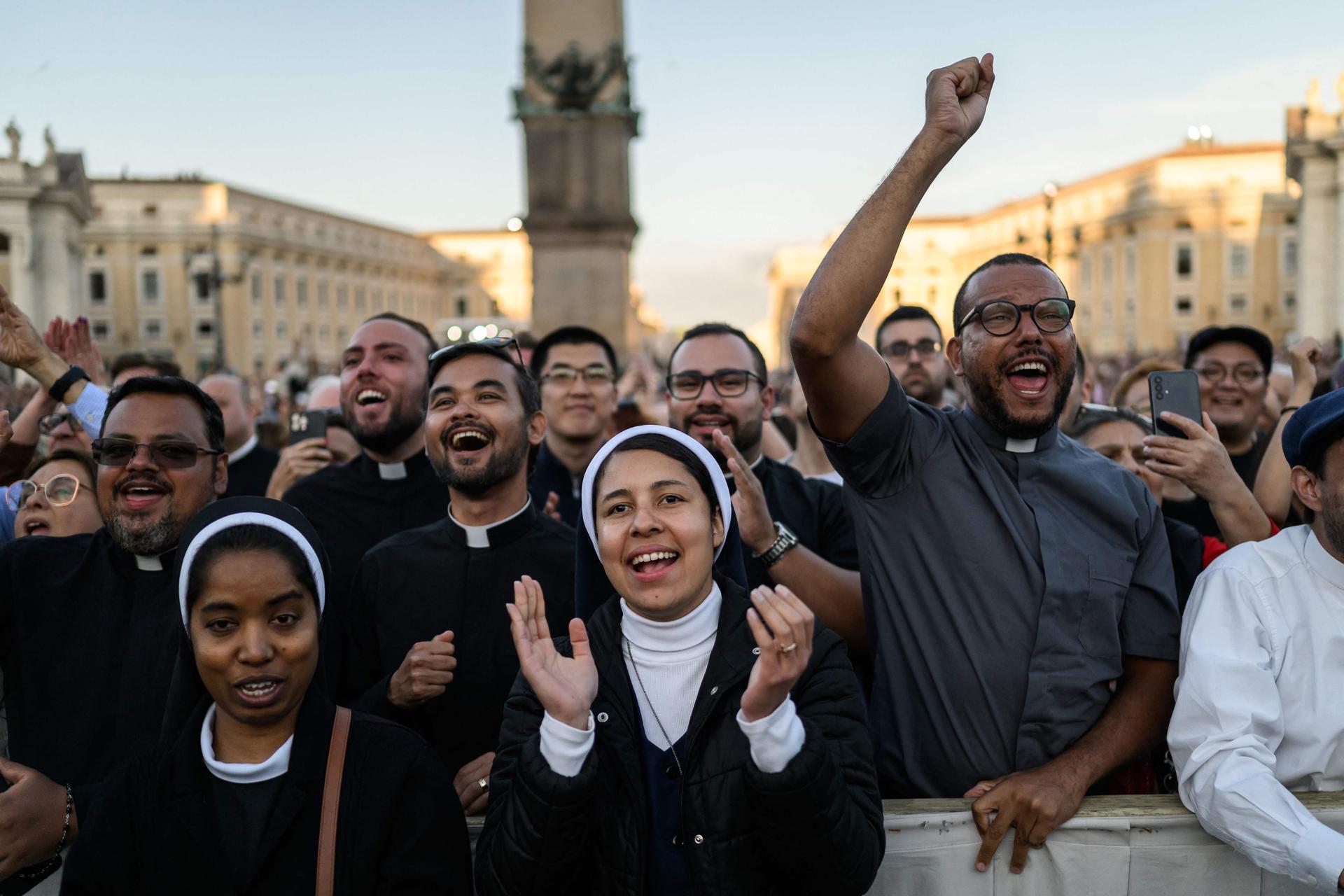 Des membres du clergé réagissent en voyant le nouveau pape Léon XIV faire sa première apparition sur le balcon de la basilique Saint-Pierre, au Vatican, le 8 mai 2025.