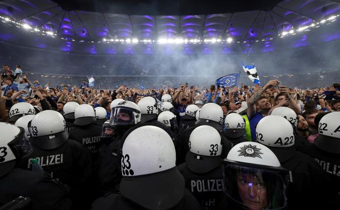 Un rang de policiers alors que les supporteurs de Hambourg envahissent le terrain pour célébrer leur promotion après un match de football de Bundesliga 2 entre Hamburger SV et SSV Ulm 1846 à Hambourg, en Allemagne, le 10 mai 2025.