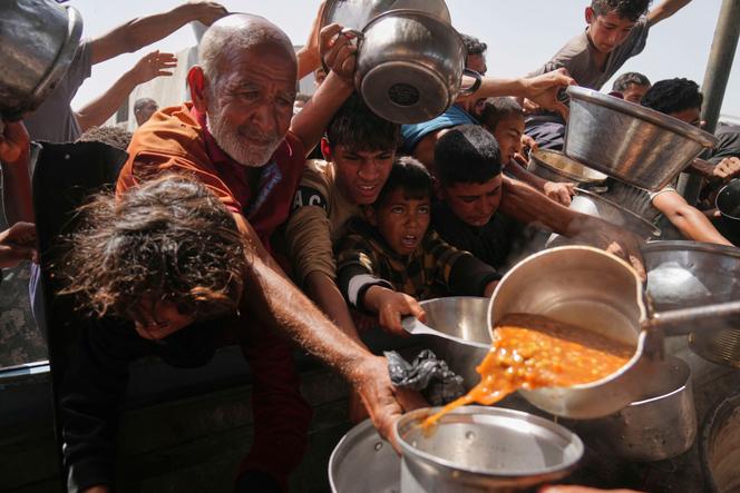 Des Palestiniens lors d’une distribution de nourriture organisée par une cuisine communautaire à Khan Younès, dans le sud de la bande de Gaza, le 11 mai 2025.