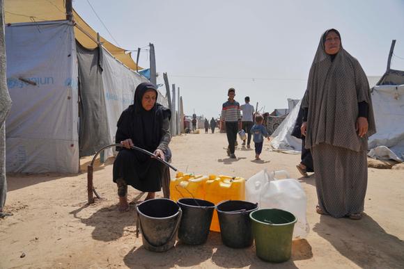 Des Palestiniennes remplissent des jerrycans d’eau, dans un camp de personnes déplacées à Khan Younès, dans la bande de Gaza, le 11 mai 2025.