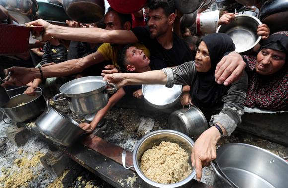 Des Palestiniens attendent de recevoir de la nourriture préparée par une cuisine caritative, à Jabaliya, dans le nord de la bande de Gaza, mercredi 14 mai 2025.