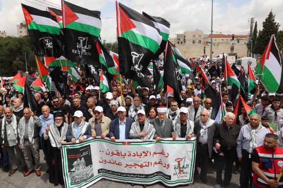 Des Palestiniens brandissent des drapeaux nationaux alors qu’ils participent à un rassemblement pour commémorer le 77e anniversaire de la Nakba, à Ramallah, en Cisjordanie, le 14 mai 2025.