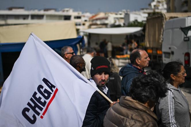 Un membre du parti d’extrême droite Chega tient un drapeau lors d’une action de campagne électorale sur le marché de Quarteira, en Algarve, le 9 avril 2025.