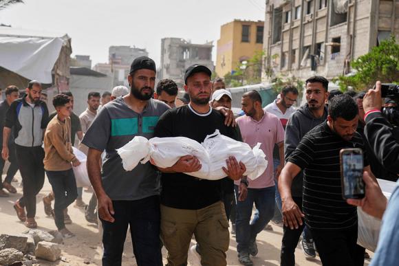 Un homme porte le corps de son neveu tué dans une frappe aérienne de l’armée israélienne, lors de ses funérailles à Khan Younès, dimanche 18 mai 2025.