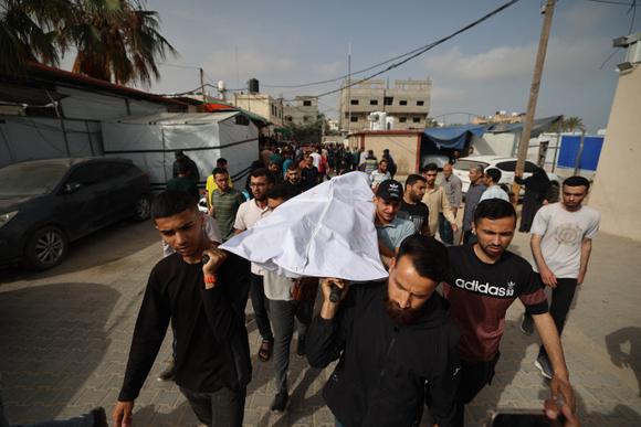 Des personnes portent le corps d’une victime des frappes israéliennes à la morgue de l’hôpital des Martyrs d’Al-Aqsa à Deir Al-Balah, dans le centre de la bande de Gaza, le 18 mai 2025.
