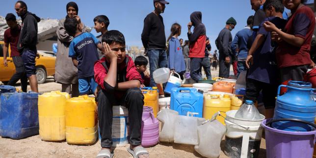 Des Palestiniens tentent de recueillir de l’eau dans un camp pour personnes déplacées dans la ville de Gaza, le 20 mai 2025.