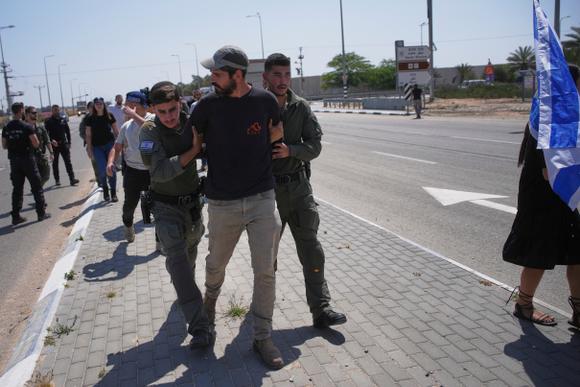 La police israélienne arrête un activiste qui bloque des camions transportant de l’aide humanitaire dans la bande de Gaza près du point de passage de Kerem Shalom, dans le sud d’Israël, le mercredi 21 mai 2025.