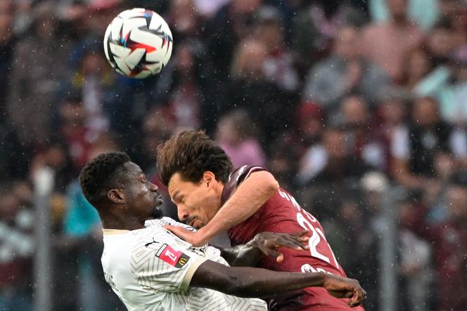 Le joueur de Reims Mory Gbane (à gauche) à la lutte aérienne avec et le Messin Benjamin Stambouli, au stade Saint-Symphorien de Metz (Moselle), mercredi 21 mai 2025.