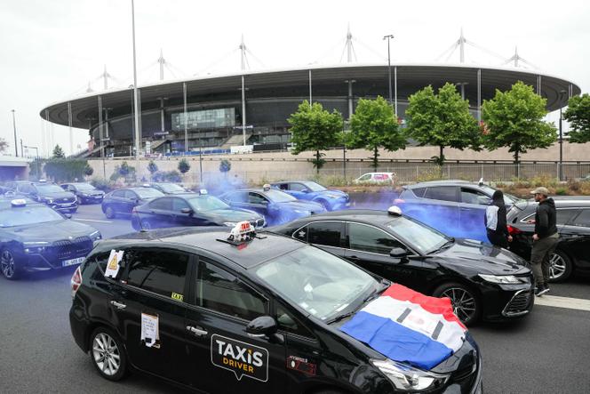 Des chauffeurs de taxi ralentissent la circulation sur l’autoroute A1, menant au centre de Paris, à la hauteur du Stade de France, alors qu’ils protestent contre les changements proposés dans la façon dont l’État finance les services de transport médical et la concurrence des voitures de tourisme avec chauffeur (VTC) qu’ils qualifient d’injustes, à Saint-Denis, au nord de Paris, le 21 mai 2025.