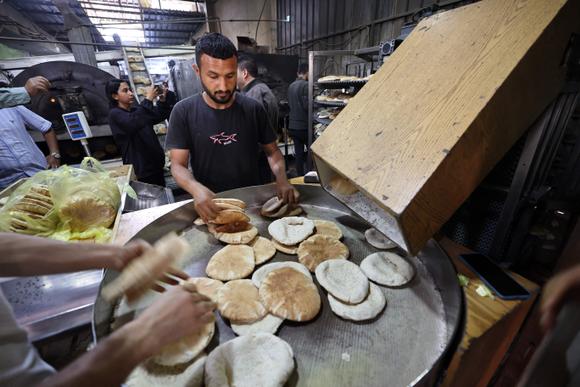 Les employés de la boulangerie remplissent des sacs de pain frais, à Deir Al-Balah, dans le centre de la bande de Gaza, le 22 mai 2025.