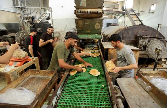 Des ouvriers palestiniens fabriquent du pain dans une boulangerie qui a repris ses activités après avoir été fermée en raison d’une pénurie de farine, à Deir Al-Balah, dans le centre de la bande de Gaza, le 22 mai 2025.