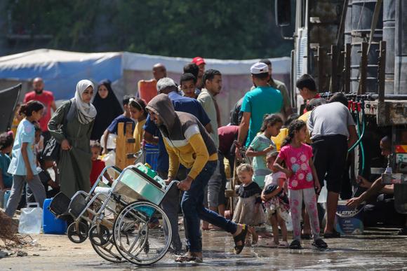 Des Palestiniens font la queue pour remplir des bidons d’eau, dans le camp de réfugiés de Nousseirat, dans le centre de la bande de Gaza, le 24 mai 2025.