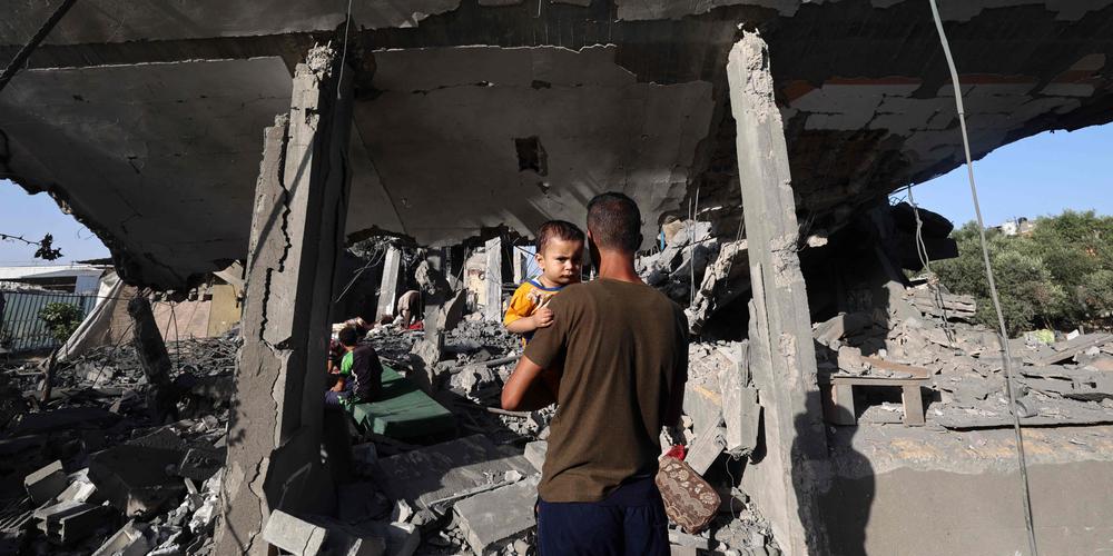 Deux Palestiniens devant les restes d’une maison visée par une frappe israélienne dans le camp de réfugiés de Nousseirat, dans le centre de la bande de Gaza, le 24 mai 2025. - EYAD BABA / AFP