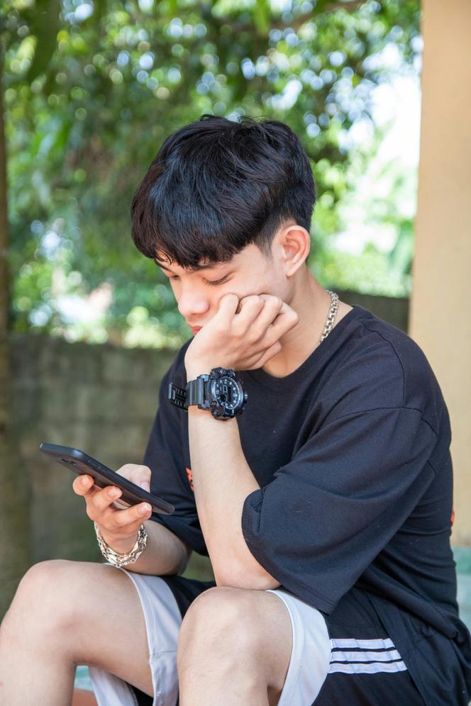 Adolescent lisant un texto sur son smartphone