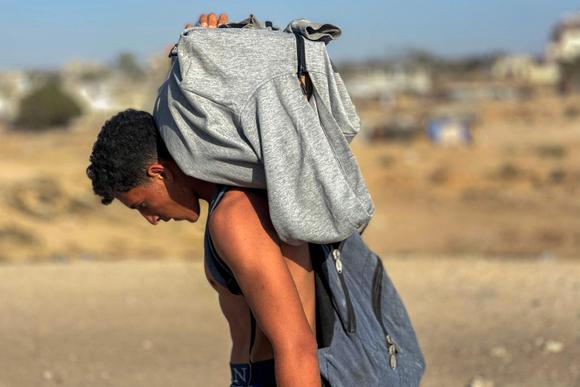 Un jeune homme porte sur son dos un colis d’aide alimentaire, à Rafah, dans le sud de la bande de Gaza, le 27 mai 2025.