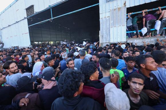 Des déplacés palestiniens se ruent dans un entrepôt du Programme alimentaire mondial où sont stockés des colis d’aide alimentaire, à Deir Al-Balah, dans le centre de la bande de Gaza, le 28 mai 2025.
