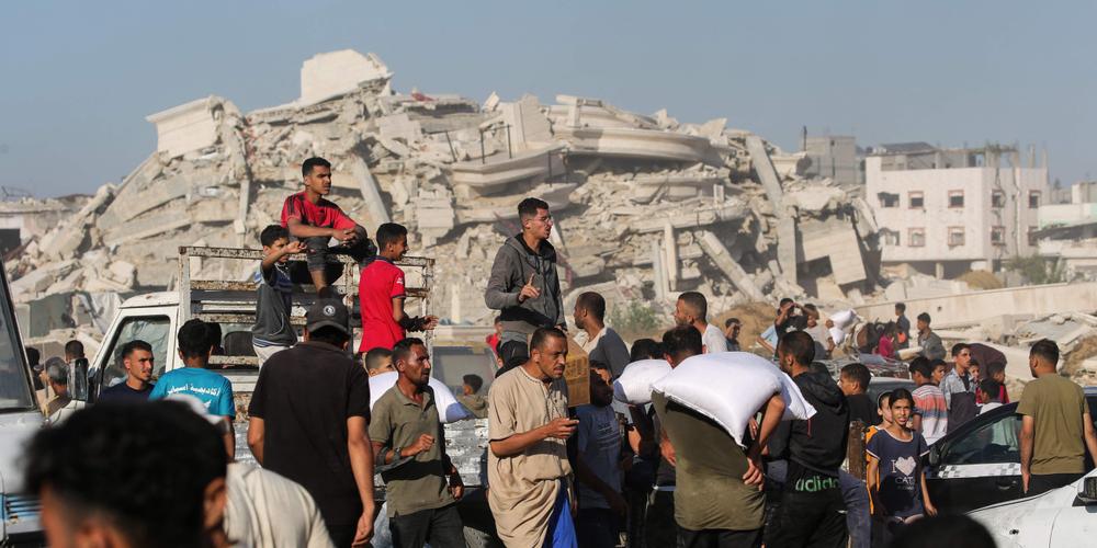 Des déplacés palestiniens transportent des sacs d’aide alimentaire après avoir pris d’assaut un entrepôt du Programme alimentaire mondial (PAM) à Deir el-Balah, dans le centre de la bande de Gaza, le 28 mai 2025. - EYAD BABA / AFP