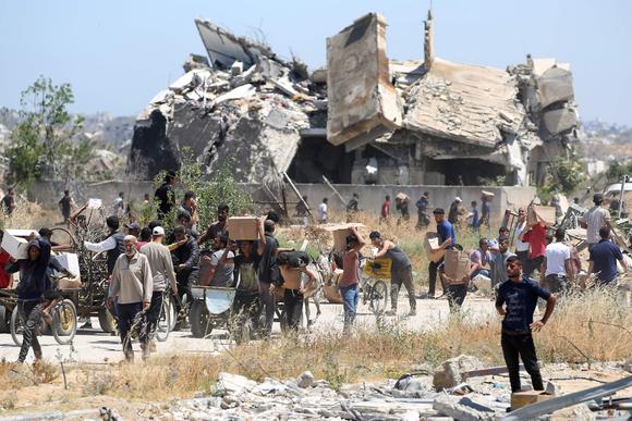 Des Gazaouis reviennent d’un centre de distribution d’aide de la Gaza Humanitarian Foundation, dans le centre de la bande de Gaza, le 29 mai 2025.