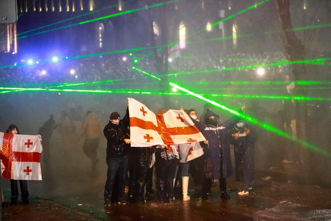 La police utilise un canon à eau pour bloquer les manifestants brandissant des drapeaux géorgiens lors d’un rassemblement contre la décision du gouvernement de suspendre les négociations d’adhésion à l’Union européenne pendant quatre ans, devant le bâtiment du Parlement à Tbilissi, en Géorgie, le  1er décembre 2024.