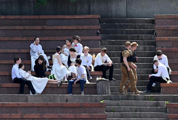 Des policiers passent devant des élèves après leur cérémonie de remise de diplômes, dans une école de Kiev, le 30 mai 2025.