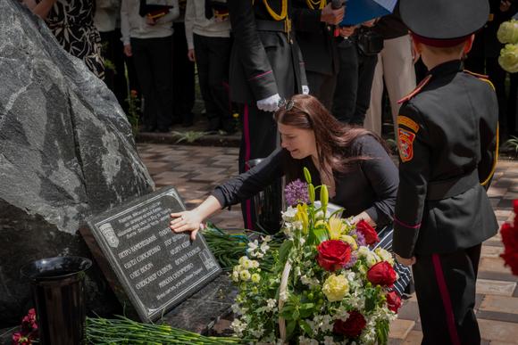 Une mère touche le nom de son fils gravé sur un mémorial dédié aux diplômés tués pendant la guerre, lors d’une cérémonie de remise des diplômes au lycée militaire de Kiev, le 30 mai 2025.