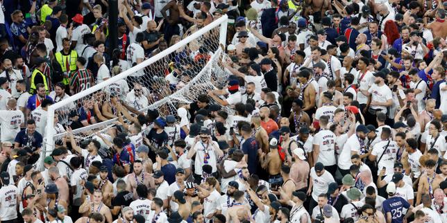 Police have to hold back PSG fans as they try to rush the field after Champions League win